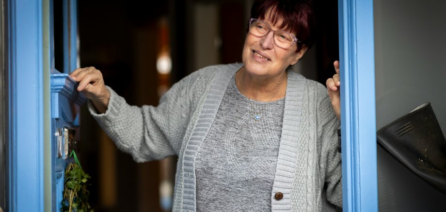 Eine Seniorin öffnet die Haustür. Eine Seniorin öffnet die Haustür.