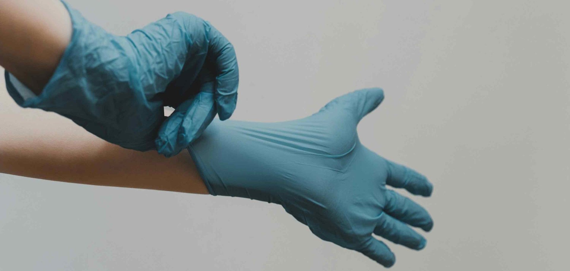 Zwei Hände in blauen Einweghandschuhen