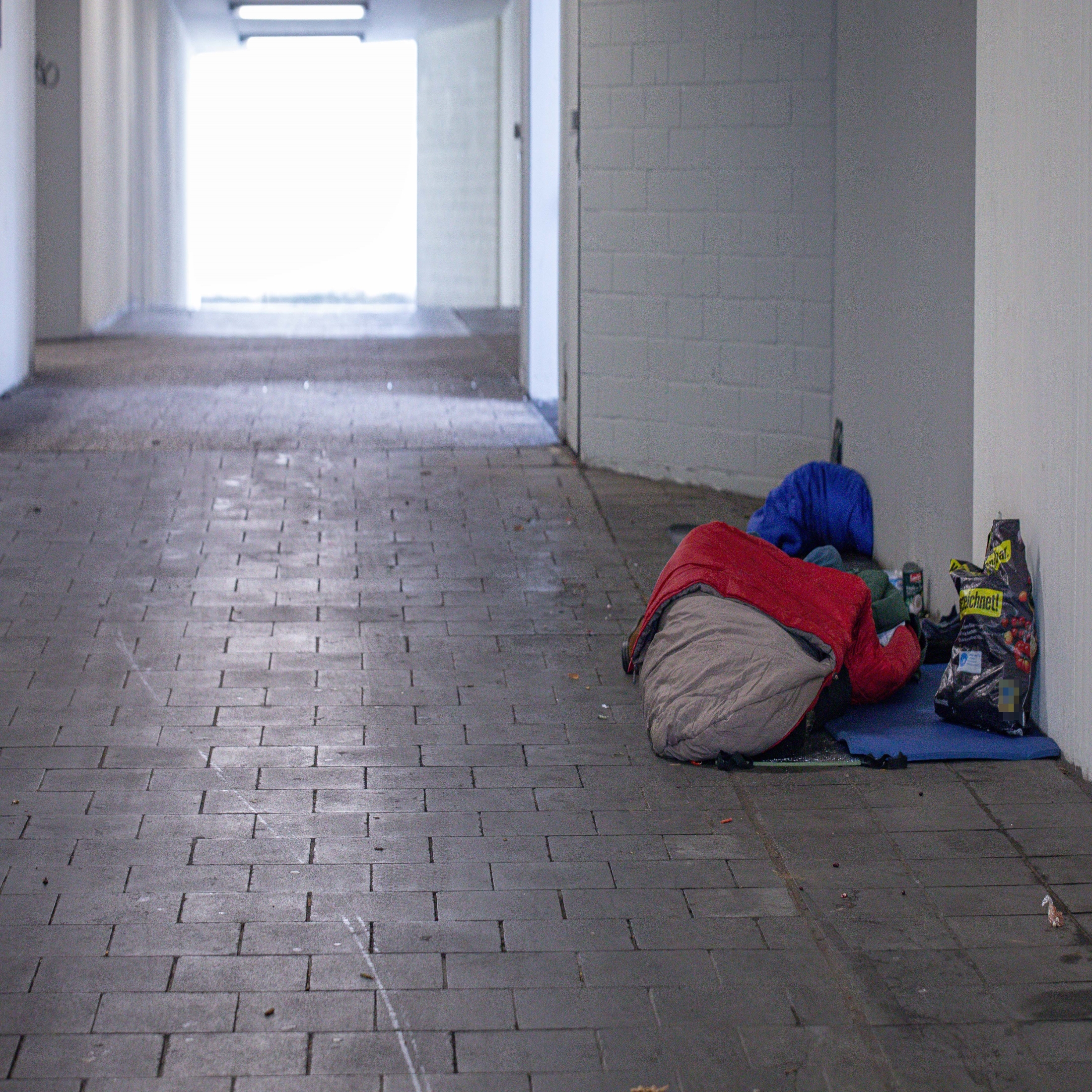 Ein Obdachloser liegt im Schlafsack in einer Unterführung.