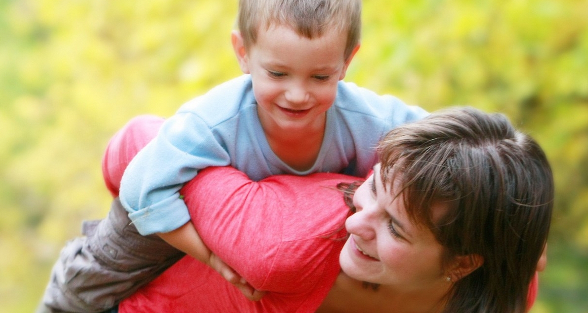 Pflegemutter mit Kind - welches sie Huckepack trägt