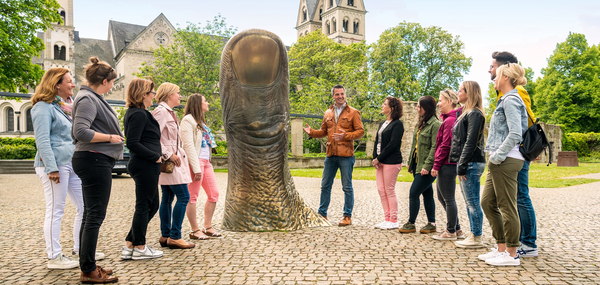 Die Stadtführungen in Koblenz starten in die neue Saison (Bild zeigt Gruppenführung an der Bronzeskulptur "Daumen" neben dem Ludwig Museum).