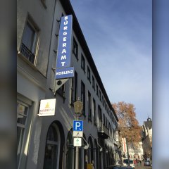 Schräge Ansicht auf die Außenfassade des Bürgeramtes Koblenz in der Gymnasialstraße mit dem Schwerbehinderparkplatz im Vordergrund