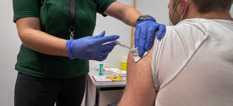Ein Mann wird geimpft - sichtbar: Eine Frau spritzt Impfstoff in den linken Oberarm eines Mannes.