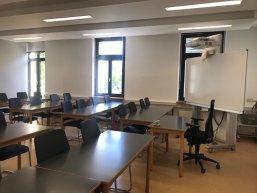 Bestuhlter Unterrichtsraum mit Beamertafel