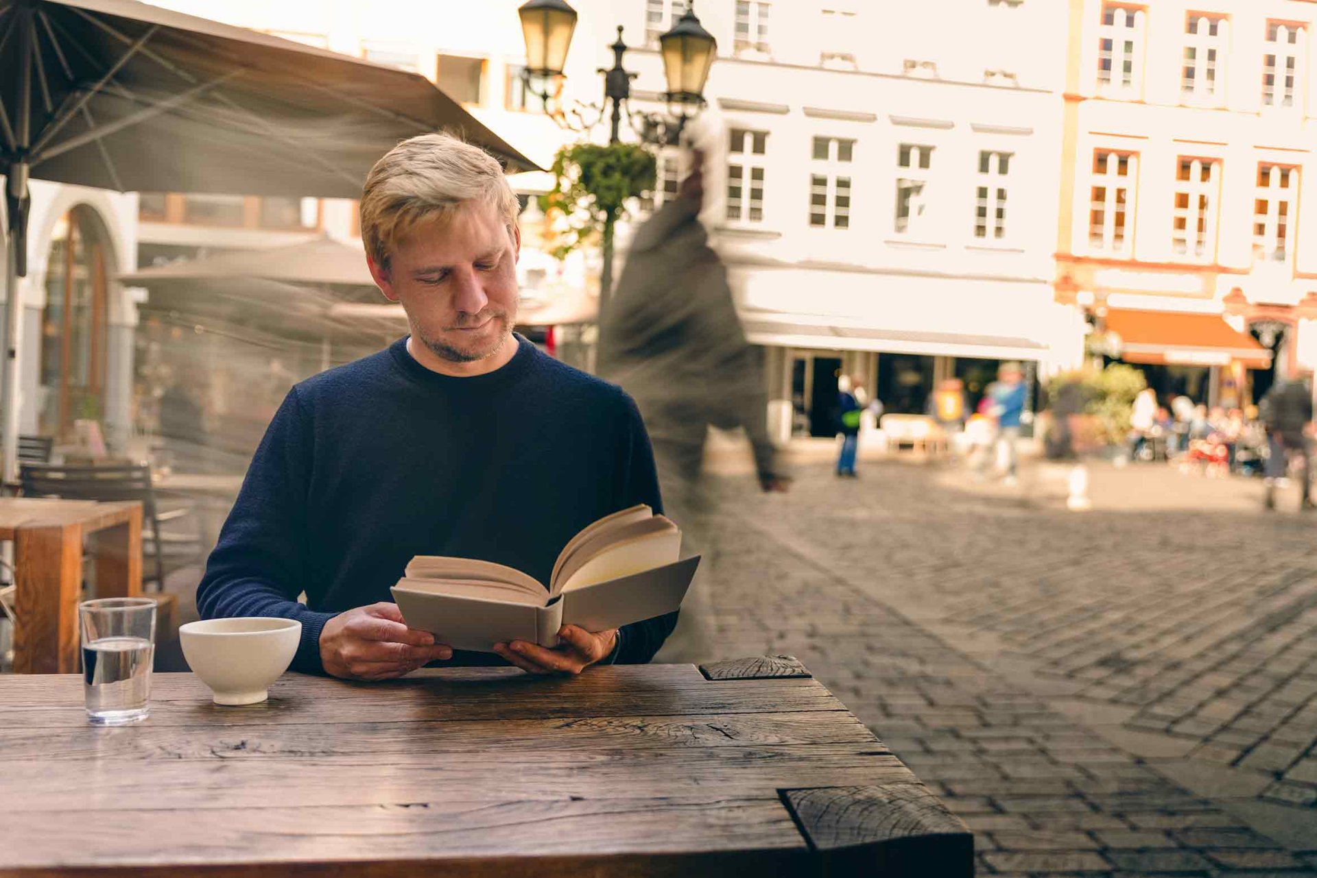 Ein Mann liest im Café ein Buch.