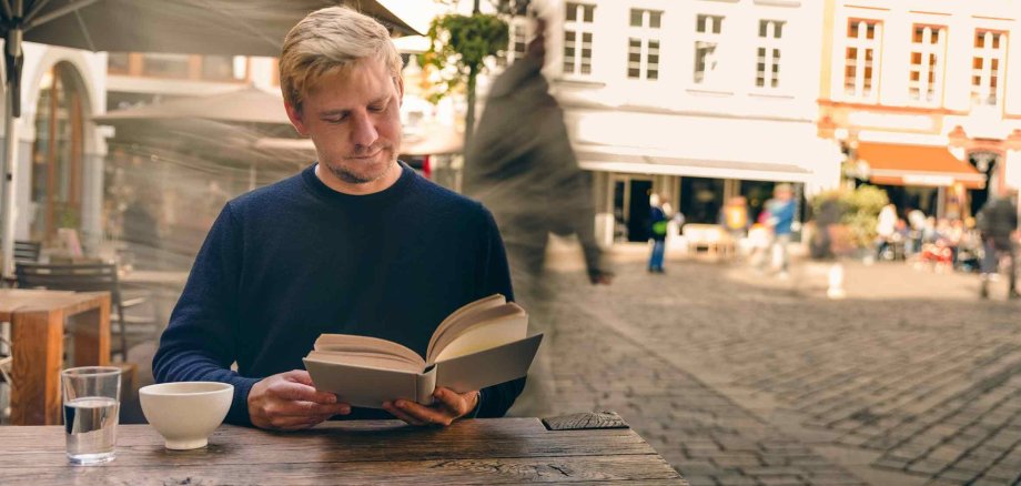 Ein Mann liest im Café ein Buch.