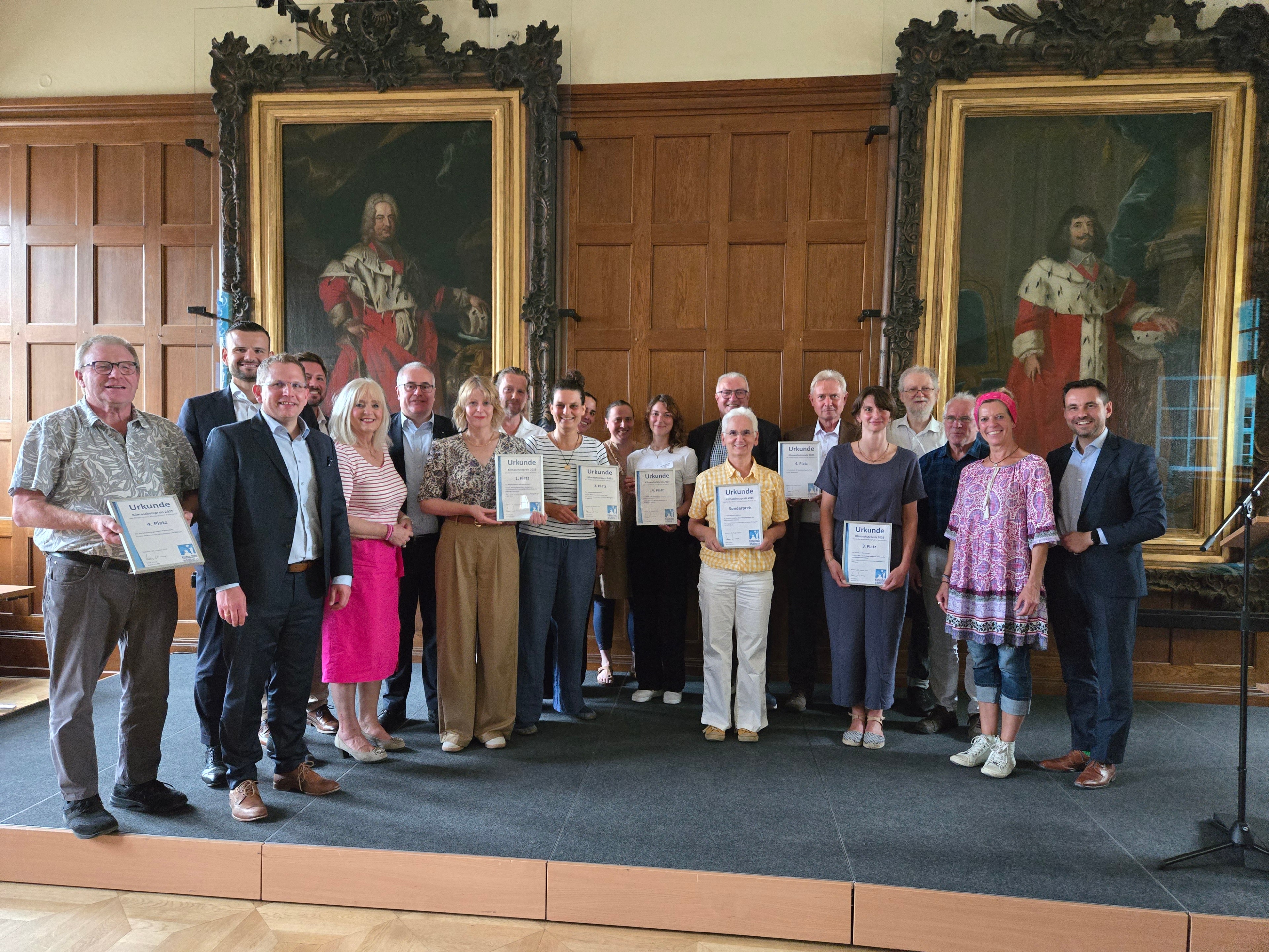 Ein Gruppenbild mit vielen Personen, teilweise halten einige Personen eine gerahmte Urkunde in den Händen.