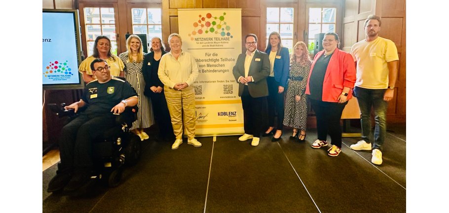 Ein größere Gruppe von Menschen steht im Halbrund, zwischen ihnen ein Roll-up.