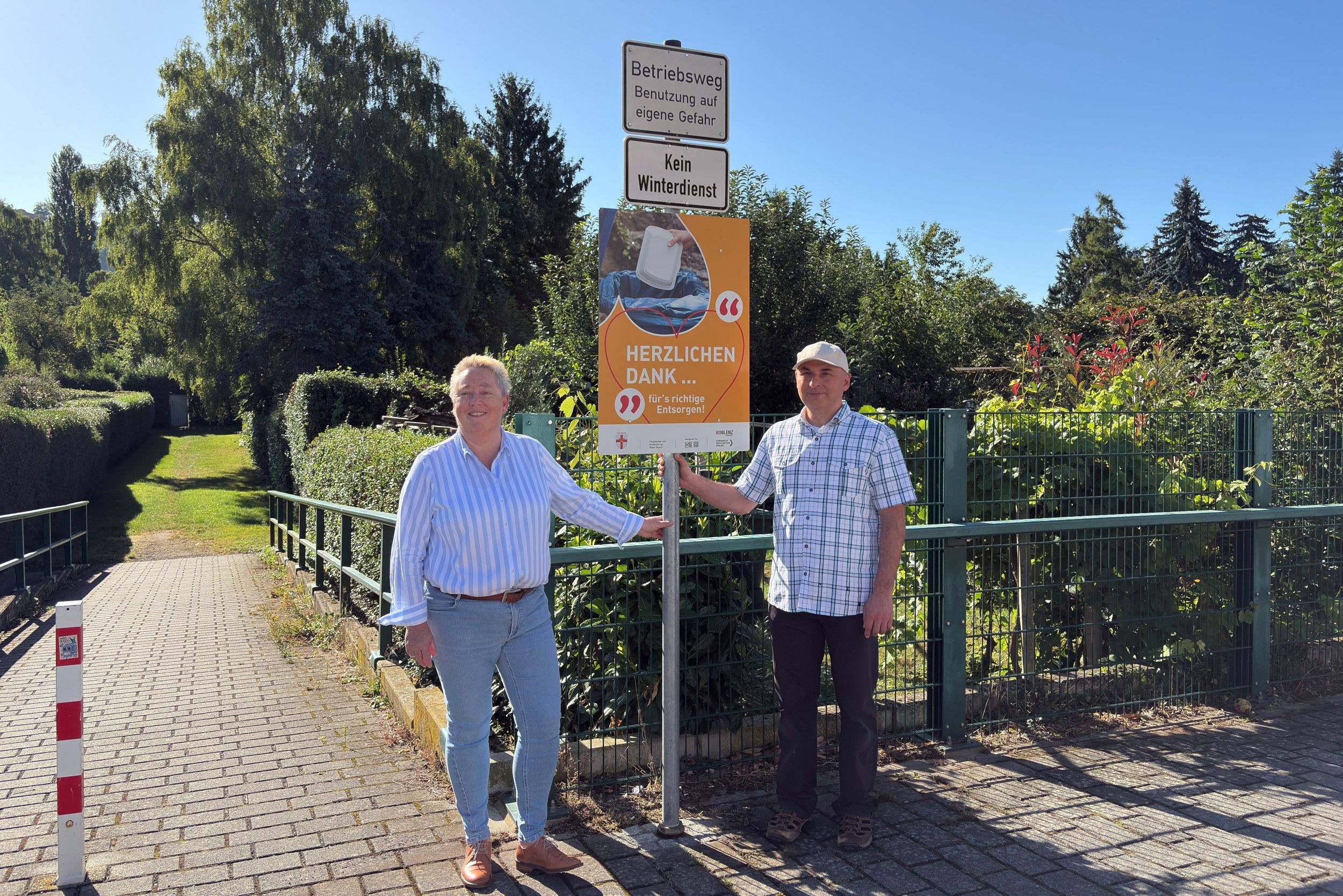 Eine Frau und ein Mann stehen neben einem Schild.