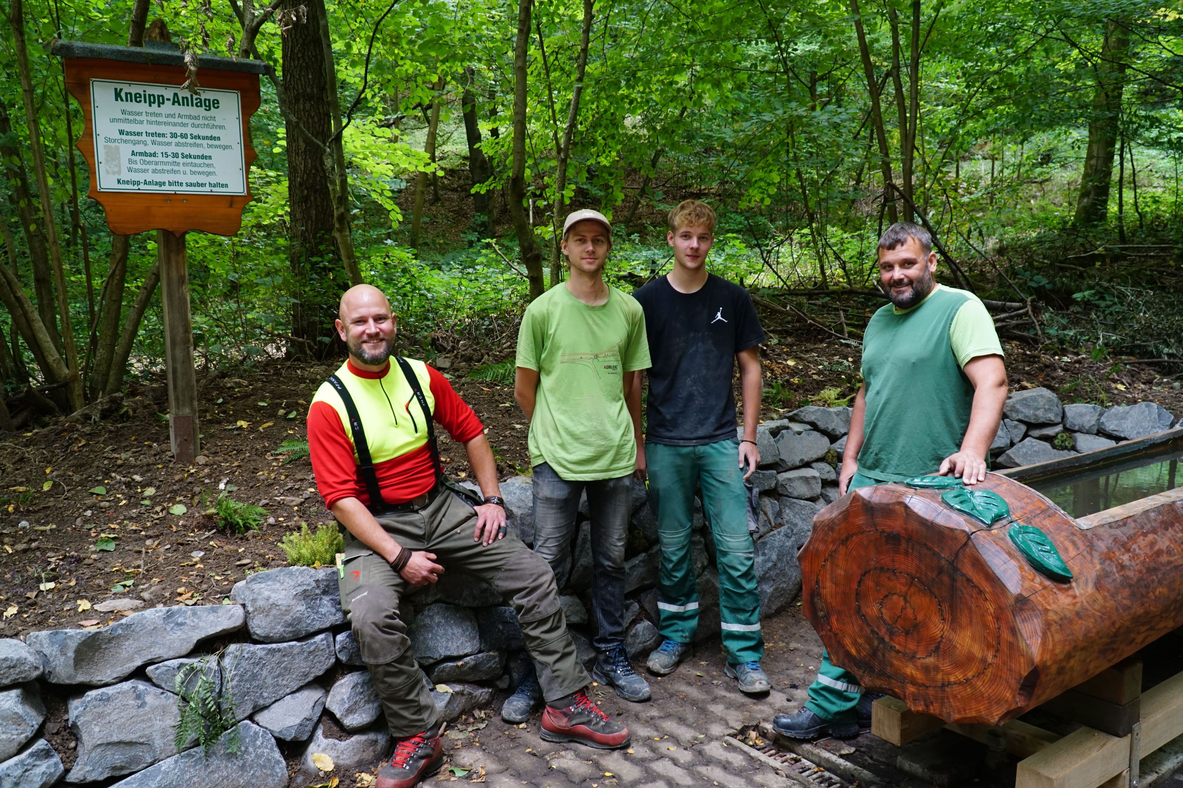 4 Männer stehen im Wald an einer Kneipp-Anlage.