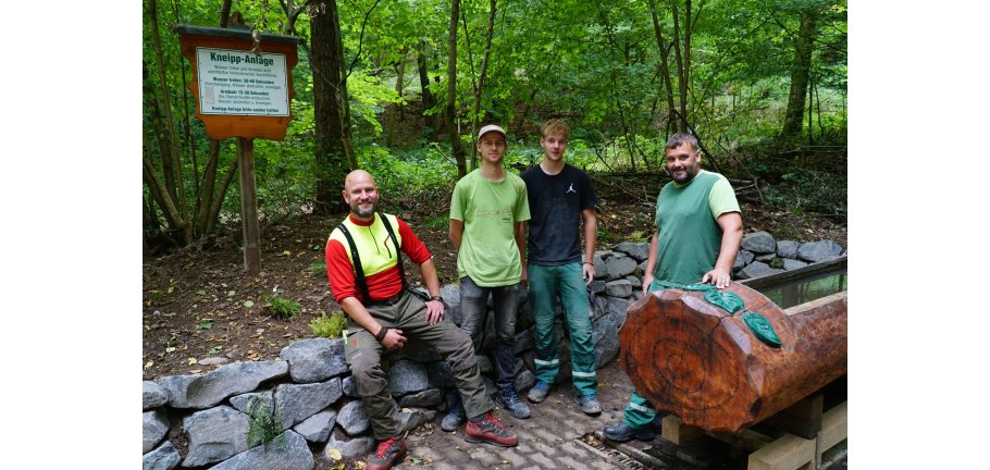 4 Männer stehen im Wald an einer Kneipp-Anlage.