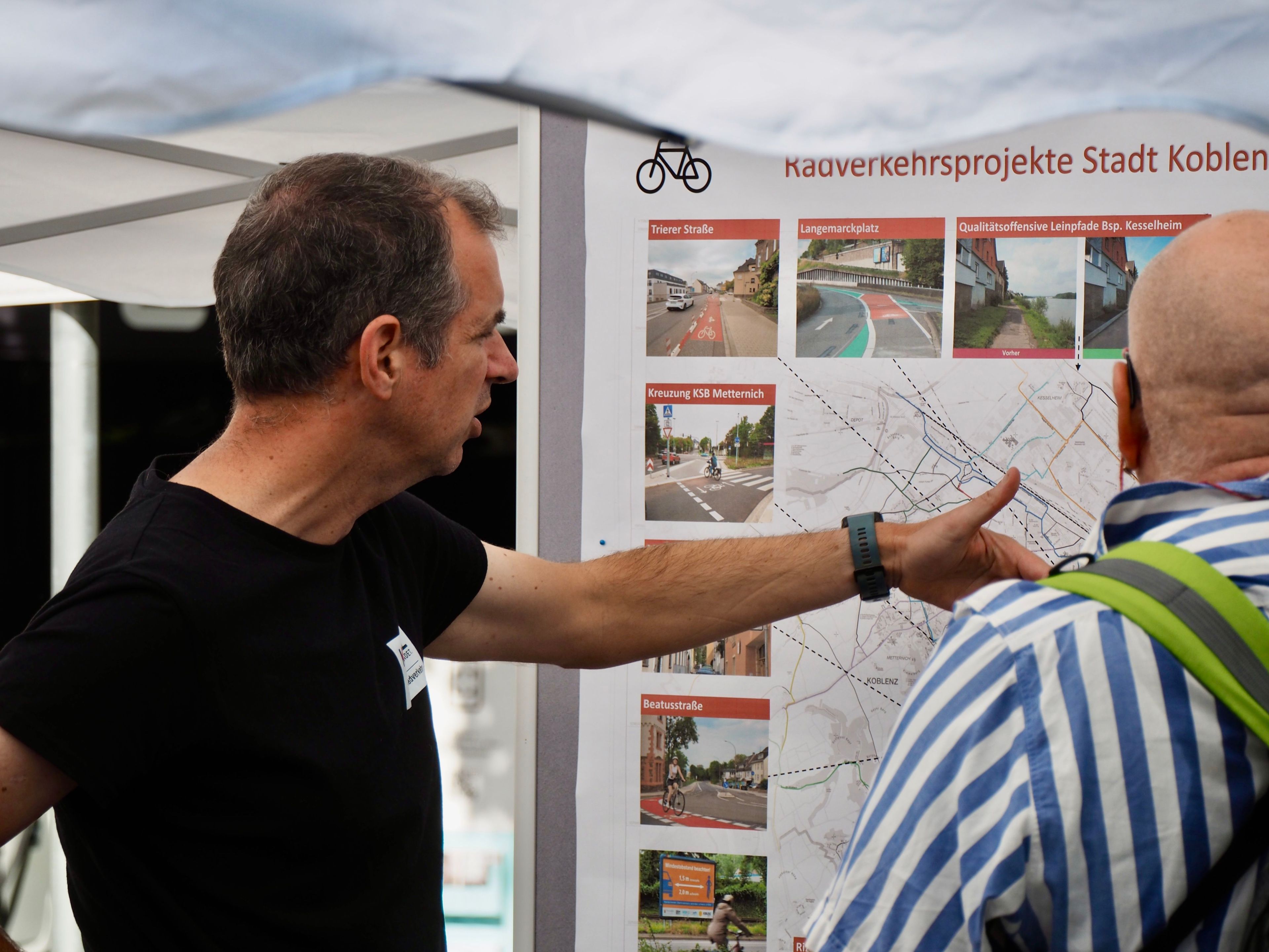 Zwei Männr stehen vor einer Karte. Einer weist erklärend auf etwas hin.