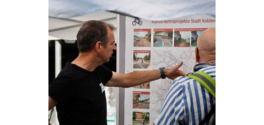 Zwei Männr stehen vor einer Karte. Einer weist erklärend auf etwas hin.