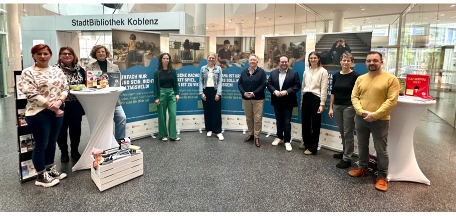 10 Personen stehen vor einem Halbkreis aus Ausstellungs-Roll ups.