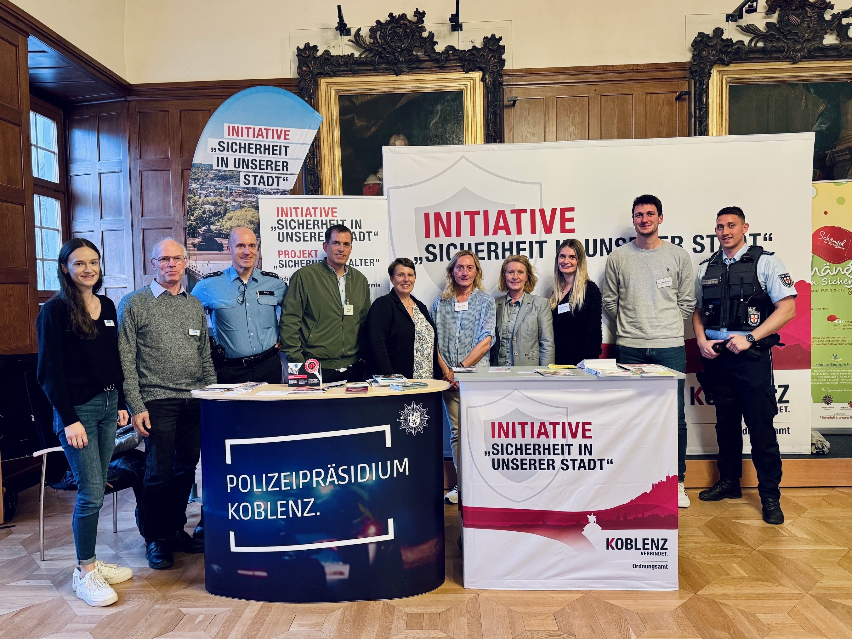 10 Personen stehen hinter 2 Ständen an denen sie Besucher beraten wollen.