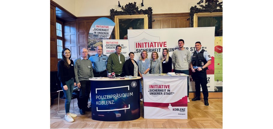 10 Personen stehen hinter 2 Ständen an denen sie Besucher beraten wollen.