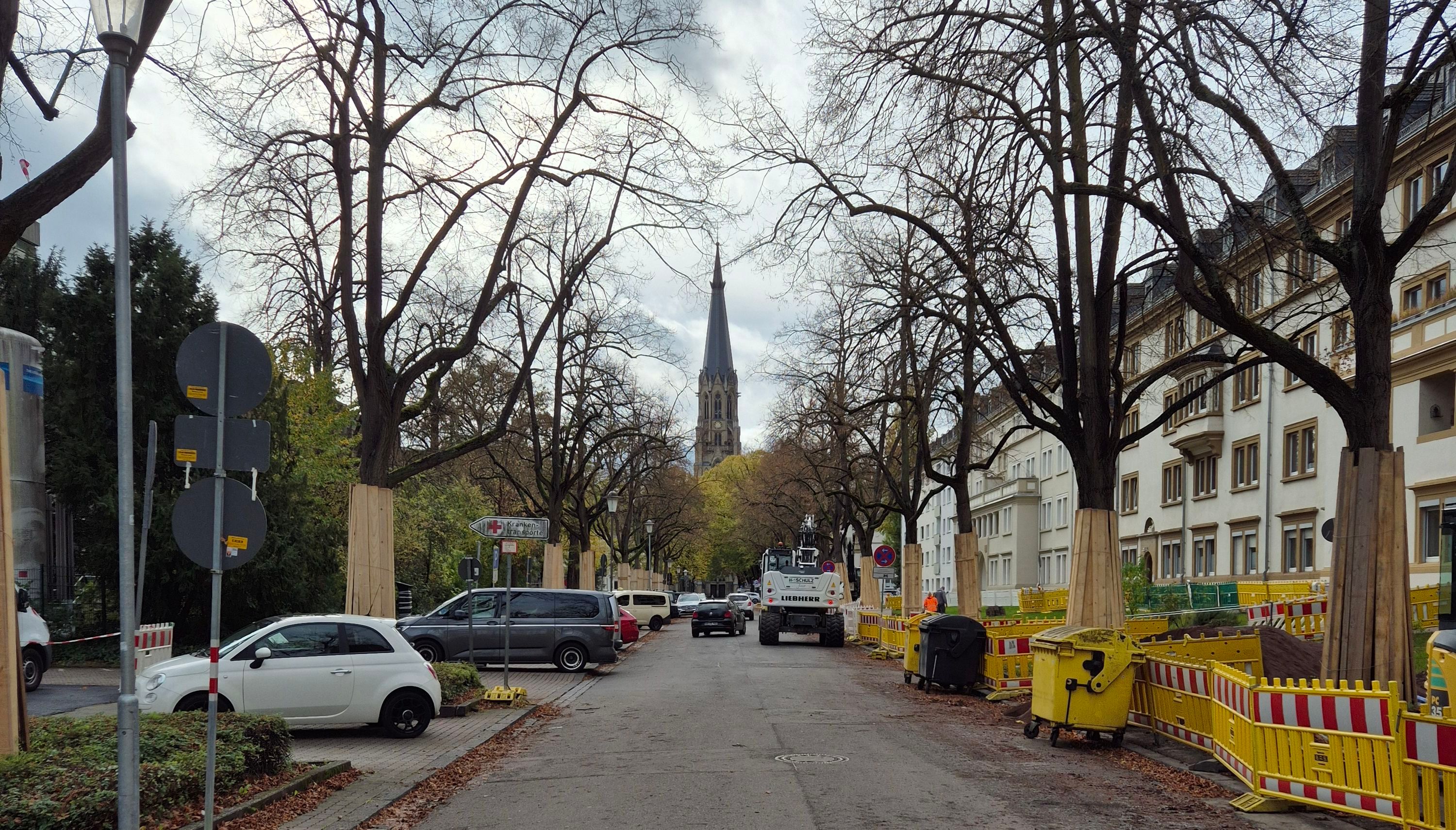 Eine Straße mit Bauzäunen und einem Bagger auf der Fahrbahn.