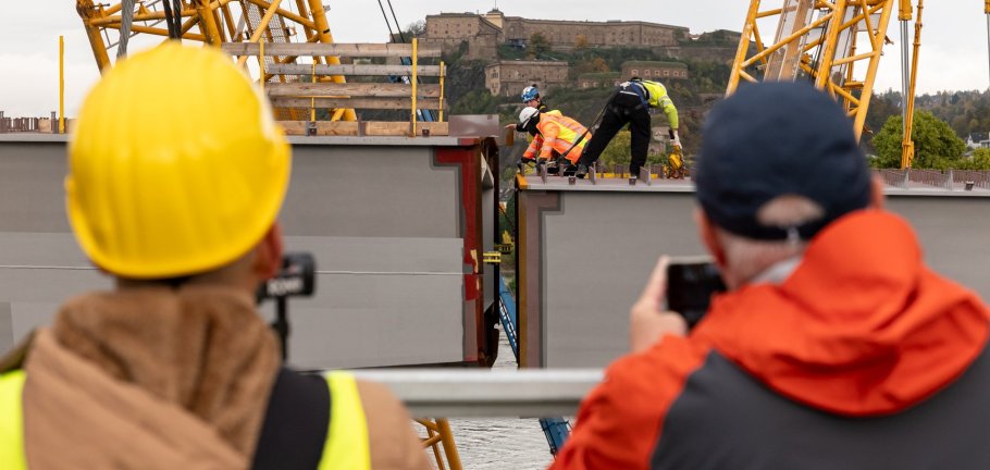 Die Einhubarbeiten für die neue Pfaffendorfer Brücke haben zahlreiche Schaulustige für Erinnerungsfotos und Videos genutzt. Schaulustige fotografieren und filmen Bauarbeiter beim Einhub eines Stahlbauteils.