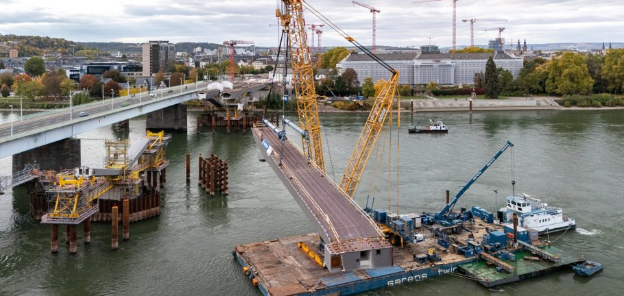 Auch auf der Pfaffendorfer Seite konnten im Oktober die ersten Stahlbauteile für die Pfaffendorfer Brücke per Kran eingehoben werden. Eine Brückenbaustelle auf dem Rhein aus der Vogelperspektive.