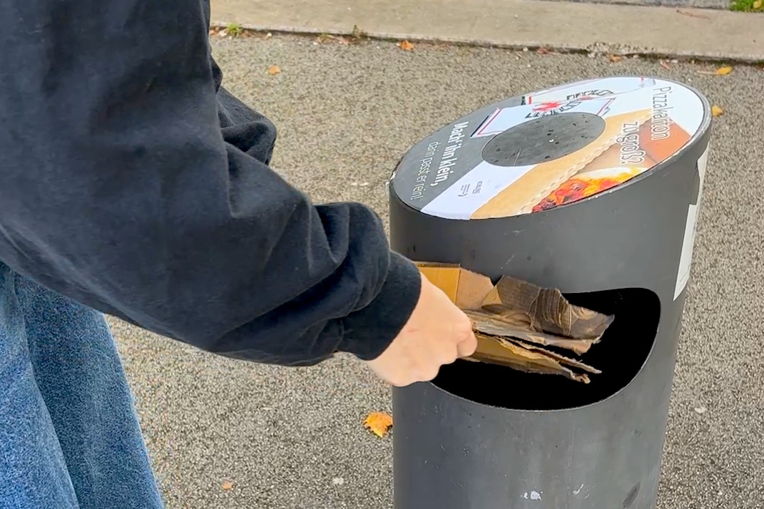 Ein öffentlicher Abfallbehälter wird befüllt.