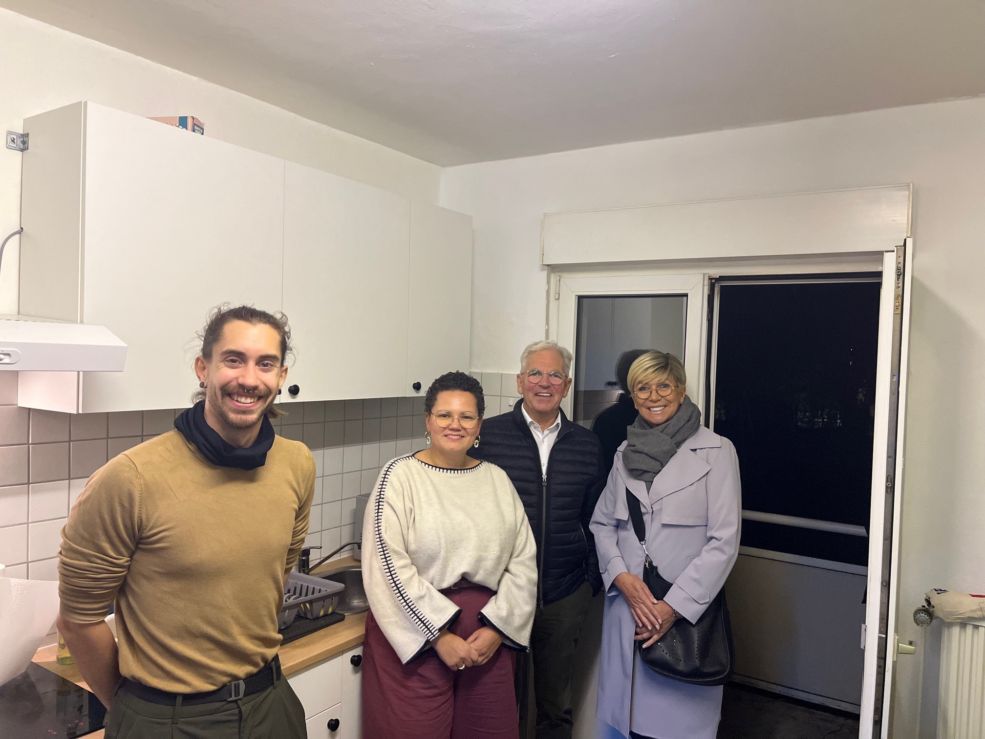 Vier Personen stehen in einer Küche.