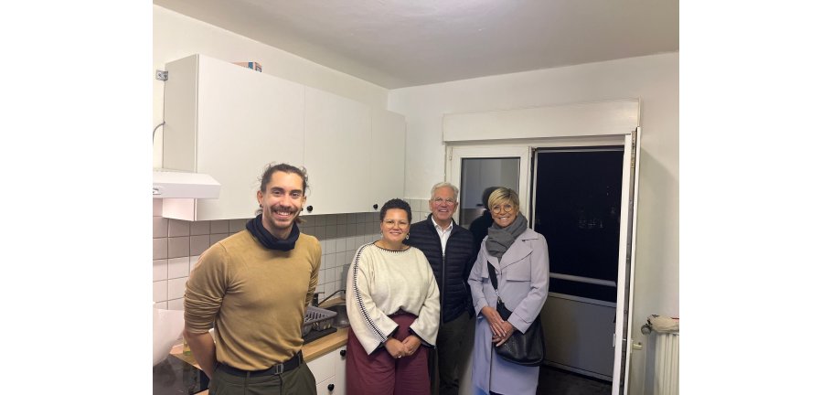 Vier Personen stehen in einer Küche.