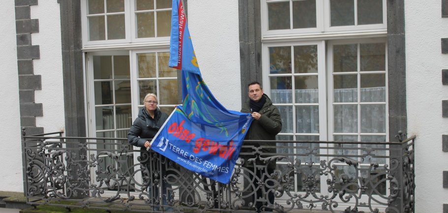 Ein Mann und eine Frau auf einem Balkon zwischen ihnen eine Fahne.