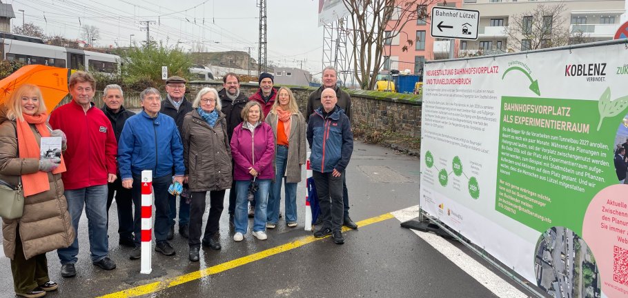 Viele Menschen neben einem Bauzaunbanner.