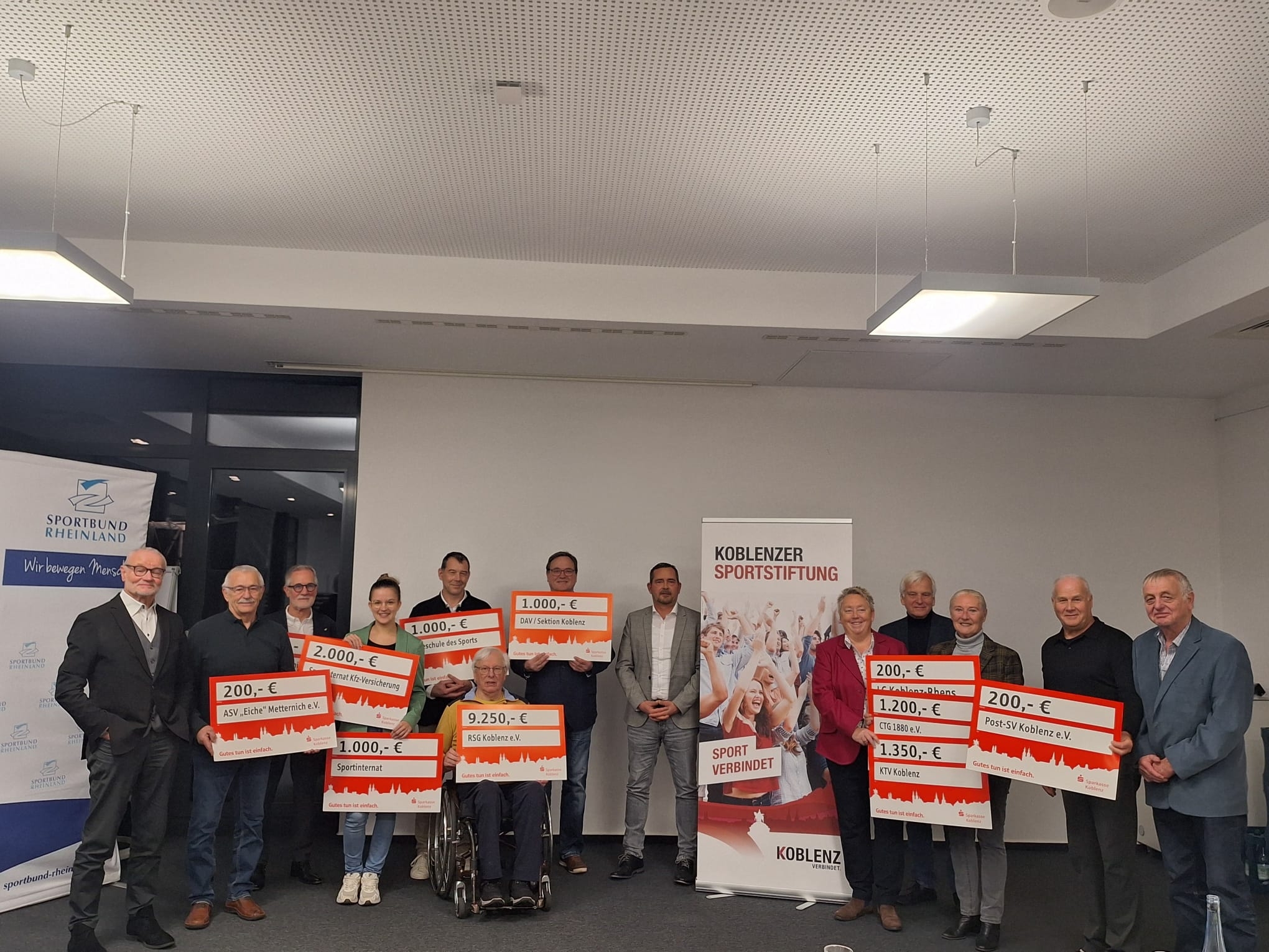 Ein Gruppenbild vieler Personen, die teilweise große Schecks halten.