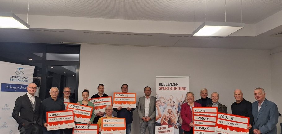 Ein Gruppenbild vieler Personen, die teilweise große Schecks halten.