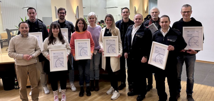 Viele Menschen zum Teil gerahmte Urkunden haltend.