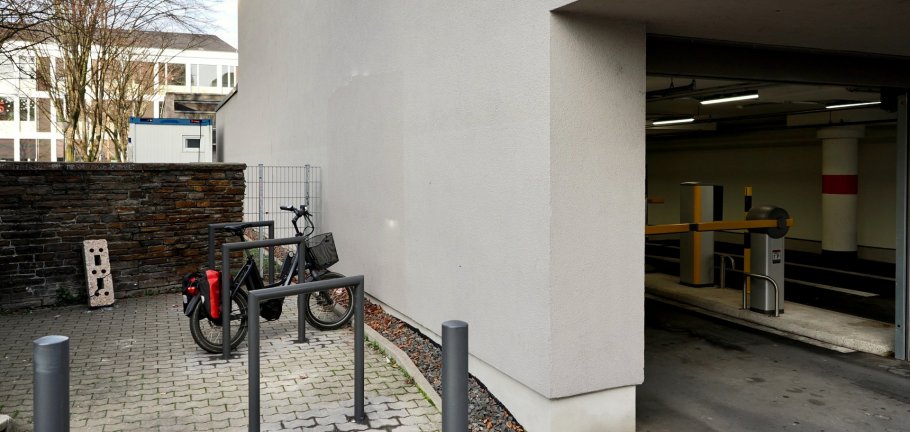 Neben einer Hauswand stehen Fahrradbügel an denen ein Rad angeschlossen ist.