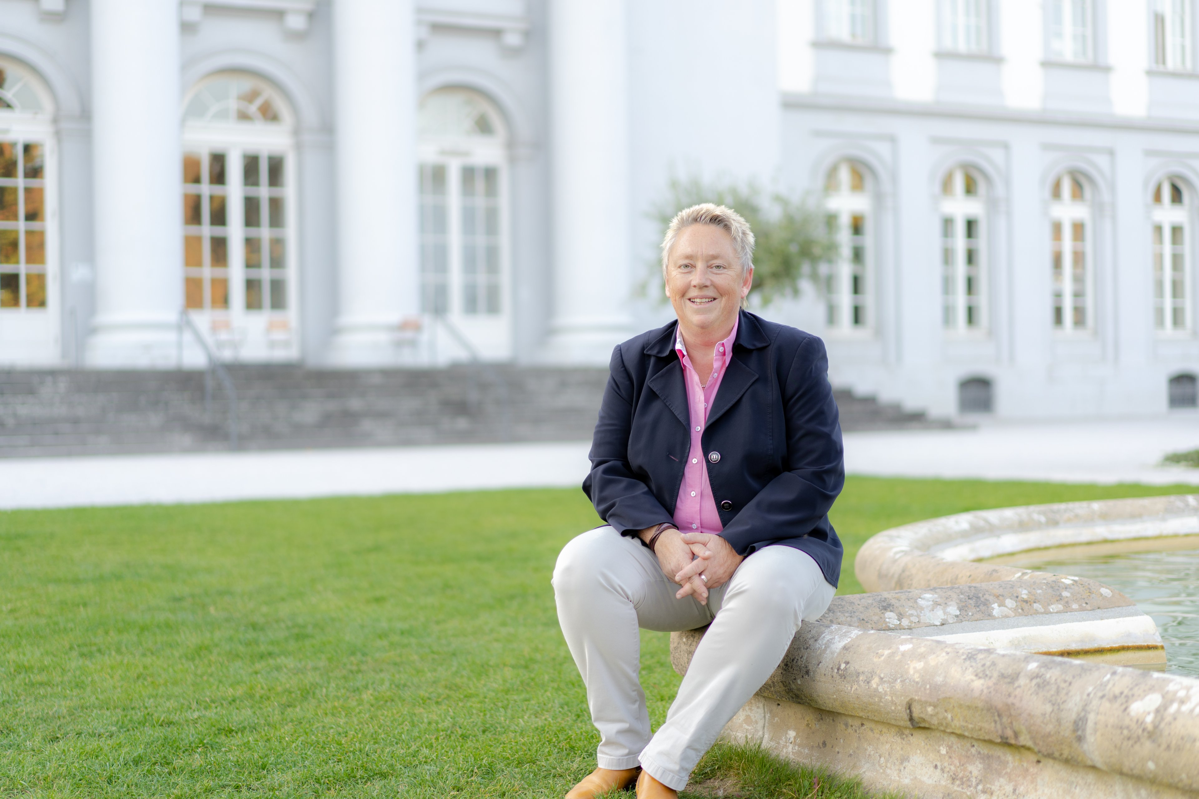 Eine Frau sitzt auf einem Brunnenrand.