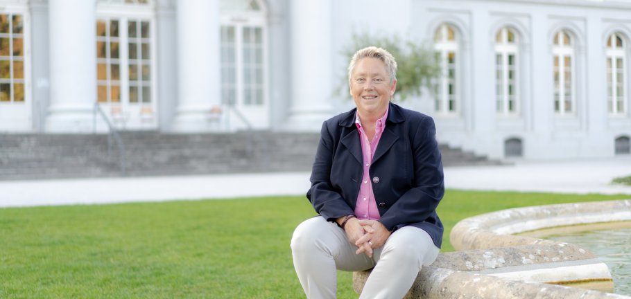 Eine Frau sitzt auf einem Brunnenrand.