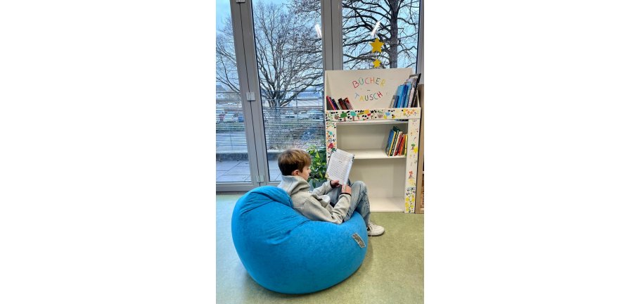 Ein Kind auf einem Sitzsack ein Buch lesend.