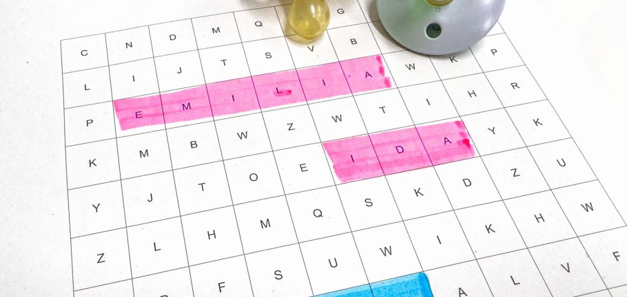 Zwei Schnuller liegen neben einem Wörterrätsel, in dem die Namen Emilia, Ida und Liam farblich markiert sind.