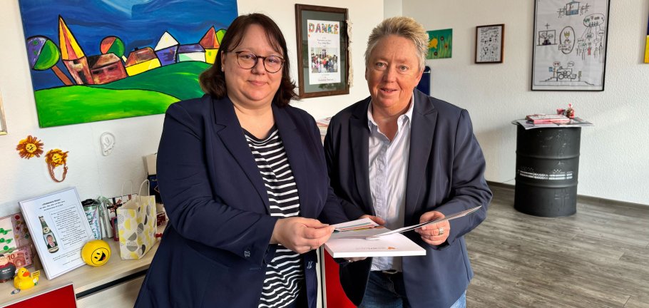 Zwei Frauen stehen in einem Raum und tauschen sich aus.