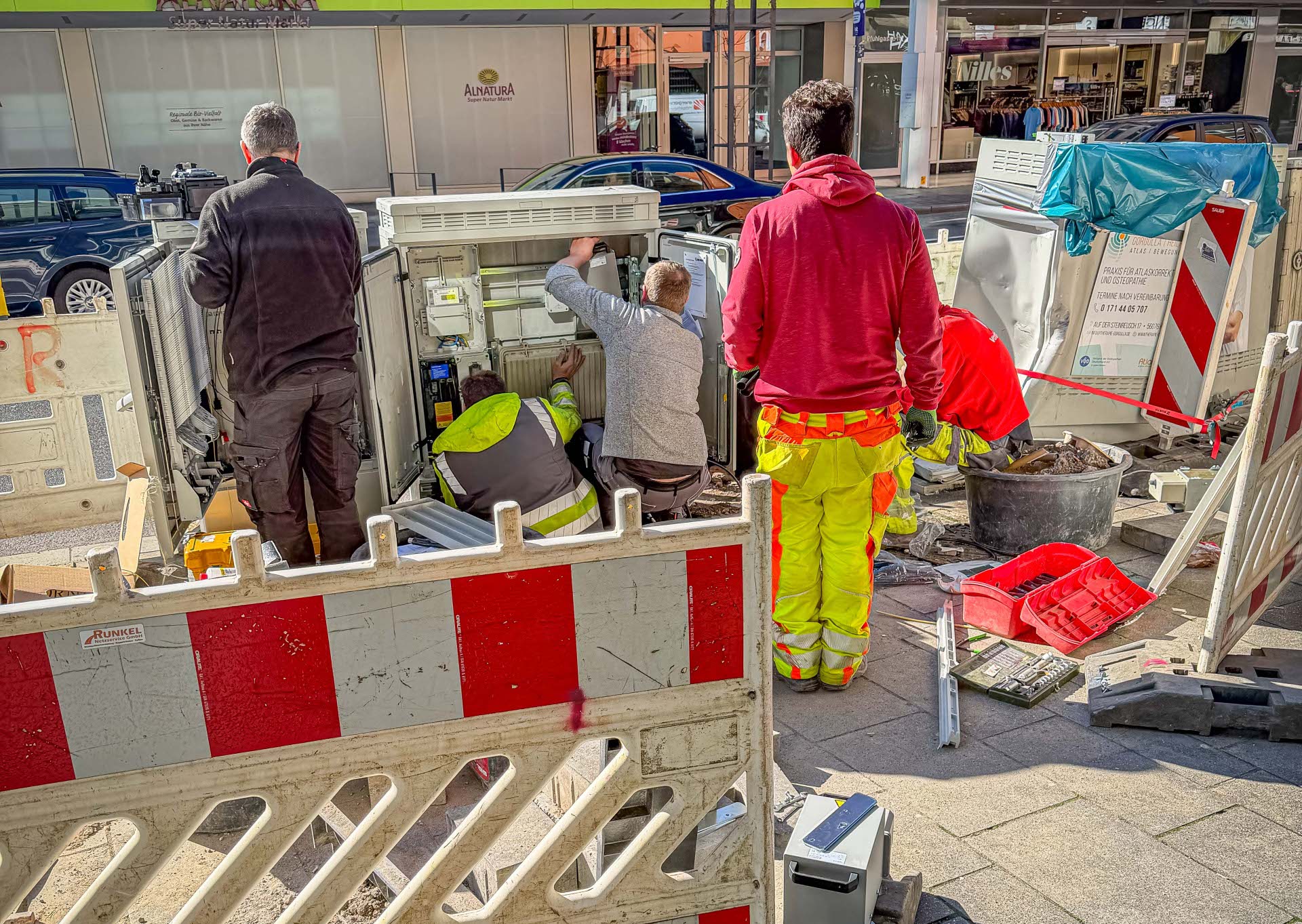 Männer reparieren einen Verteilerkasten an einer Straße.