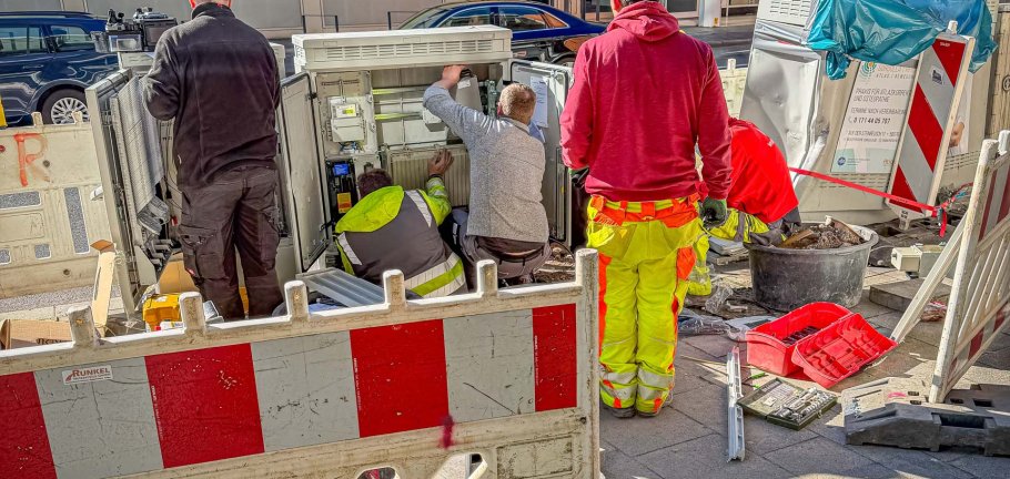 Männer reparieren einen Verteilerkasten an einer Straße.