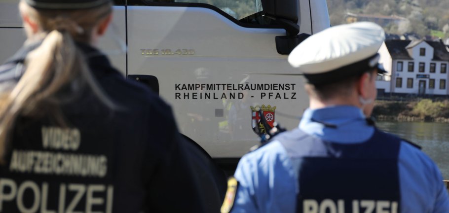 Zwei Polizisten stehen vor einer LKW-Tür mit der Aufschrift Kampfmittelräumdienst Rheinland-Pfalz. Zwei Polizisten stehen vor einer LKW-Tür mit der Aufschrift Kampfmittelräumdienst Rheinland-Pfalz.