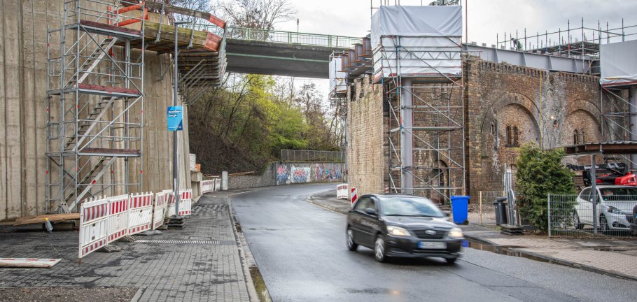 Ein Auto fährt auf einer Straße durch eine Brücke, an der Bauarbeiten stattfinden.