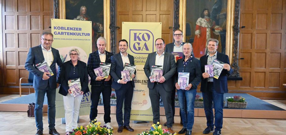 Dank einer starken Kooperation startet die Koblenzer Gartenkultur mit zahlreichen attraktiven Veranstaltungen in ihre 15. Saison. Oberbürgermeister David Langner (Mitte) und Kultur- und Bildungsdezernent Ingo Schneider (4. v.r.) stellten die neue Programmbroschüre sowie das Glüxmagazin „Erlebnis Koblenz“ von Lotto Rheinland-Pfalz vor.