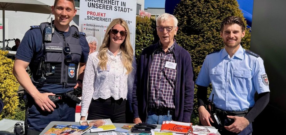 Vier Personen stehen an einem Informationsstand.