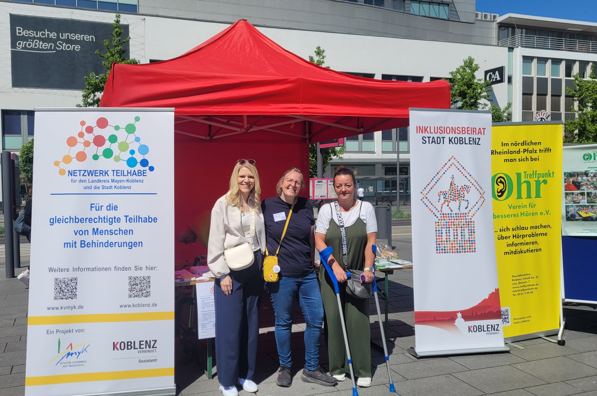 Drei Frauen stehen vor einem Informationsstand.