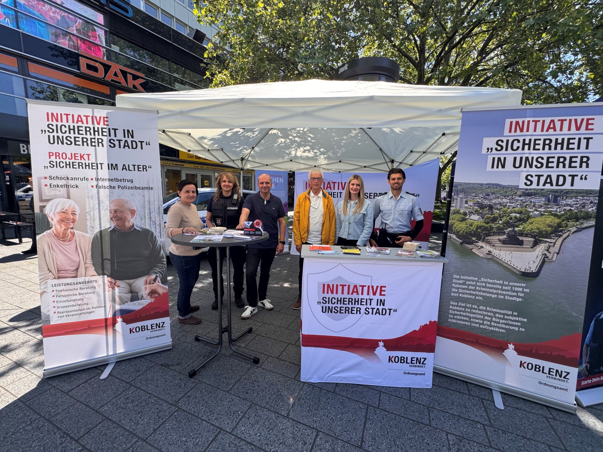 Frauen und Männer stehen an einem Infostand.