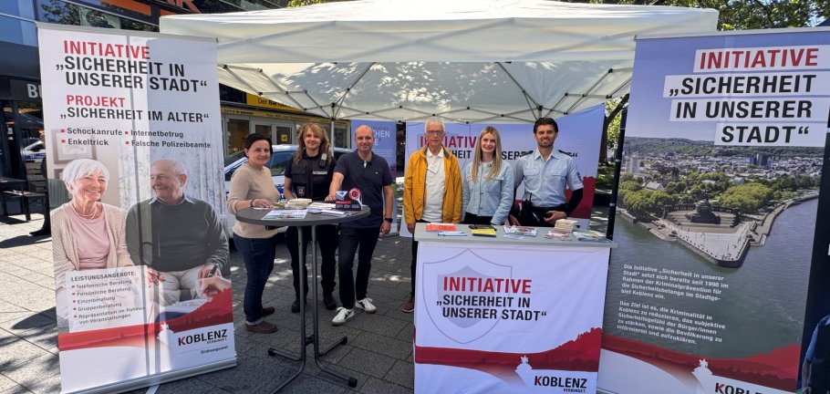 Frauen und Männer stehen an einem Infostand.