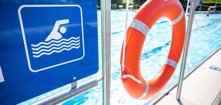Ein Schild mit einem Schwimmersymbol neben einem Rettungsring. Ein Schild mit einem Schwimmersymbol neben einem Rettungsring.