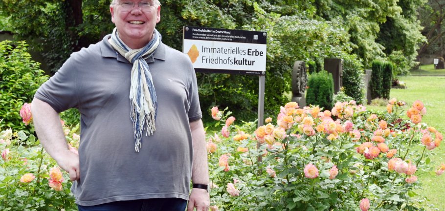 Ein Mann steht vor einem Rosenstrauch. Ein Mann steht vor einem Rosenstrauch.