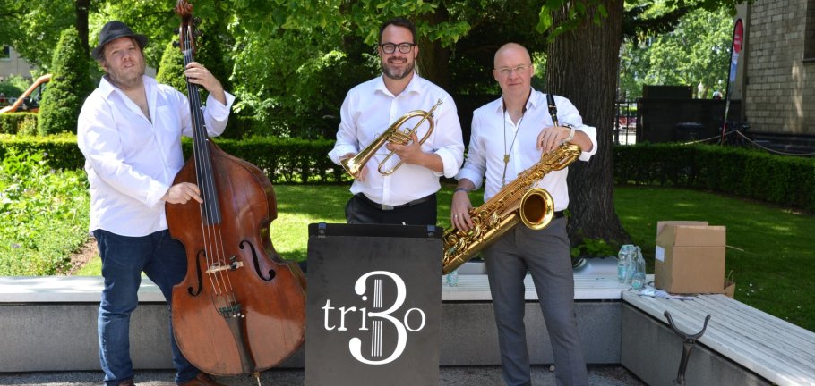 Drei Männer stehen mit Instrumenten in einem Park. Drei Männer stehen mit Instrumenten in einem Park.