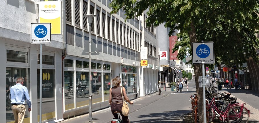 Eine Radfahrerin fährt an einem Straßenschild vorbei, dass eine Fahrradstraße ankündigt.